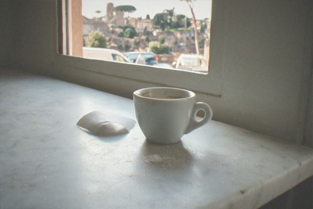 An espresso cup and a receipt on the marble counter of a Roman café