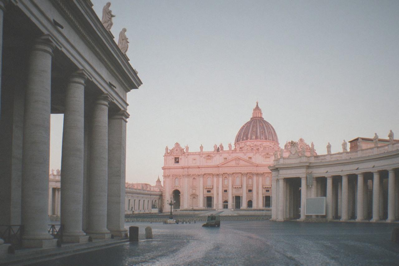 Empty St Peter's Square at dawn with the basilica facade and colonnades in soft light