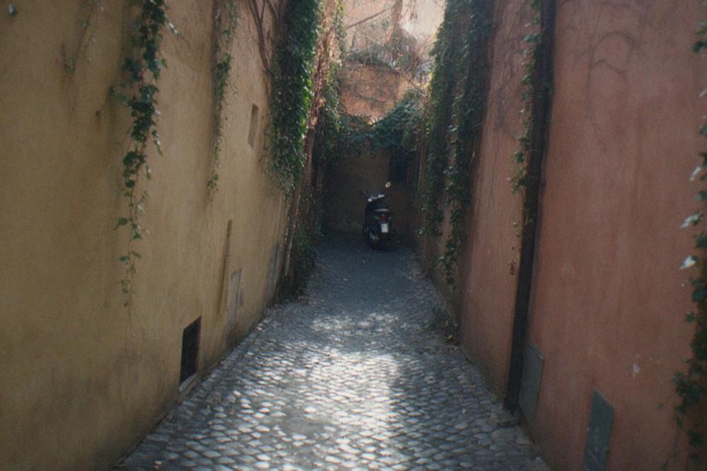 A narrow cobblestone street in central Rome lined by ochre and terracotta buildings