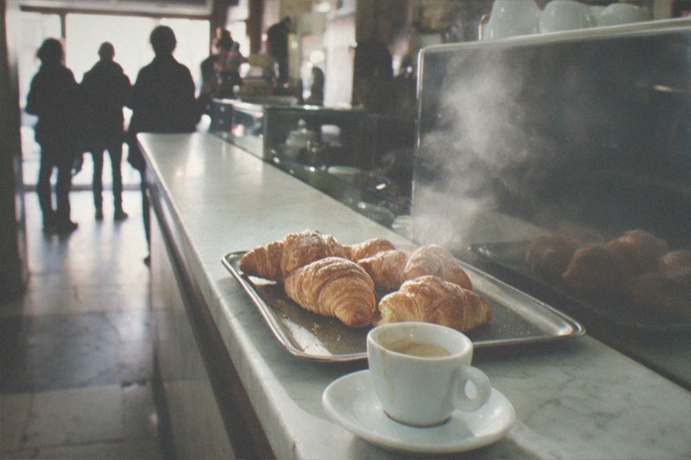Roman bar counter with a coffee cup and pastries in morning light