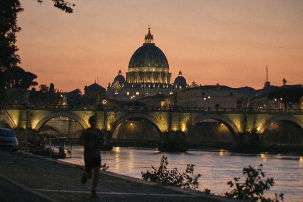 The dome of St Peter's Basilica silhouetted against a warm orange sky during the golden hour
