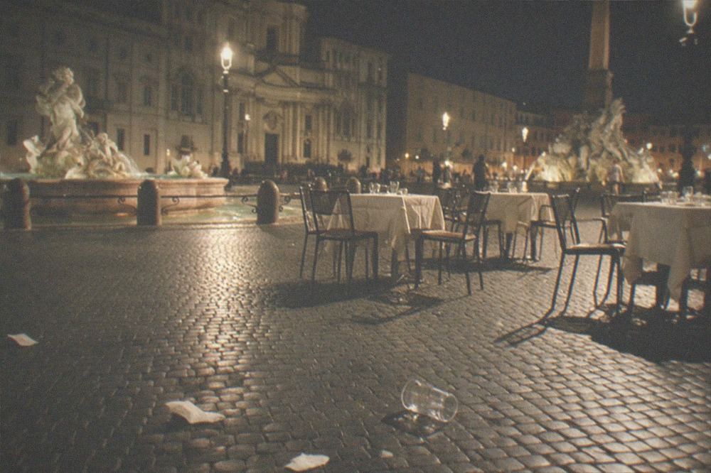 Crowded Rome piazza at night with street lamps and outdoor tables