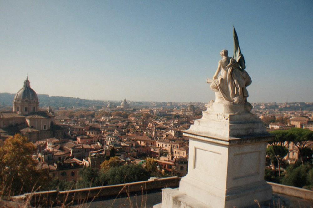 The view from the Gianicolo hill over Rome at midday, with the dome of St Peter's on the left and the Vittoriano monument in the centre, on a bright autumn day.
