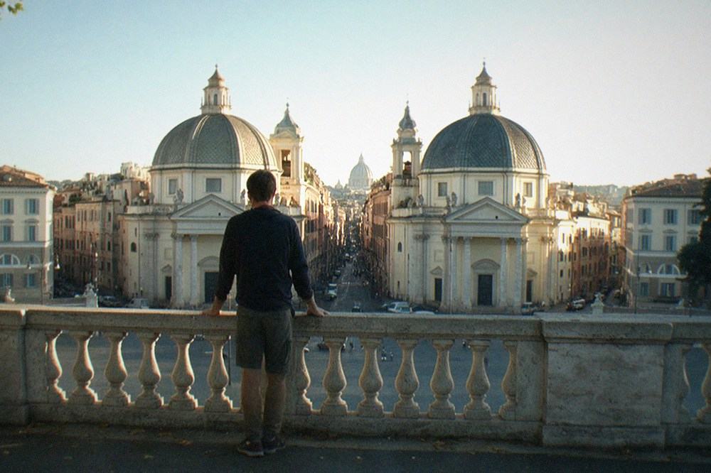 The Pincio terrace in Villa Borghese on a late afternoon, with a railing overlooking the Piazza del Popolo and the twin churches, and the dome of St Peter's in the distance.