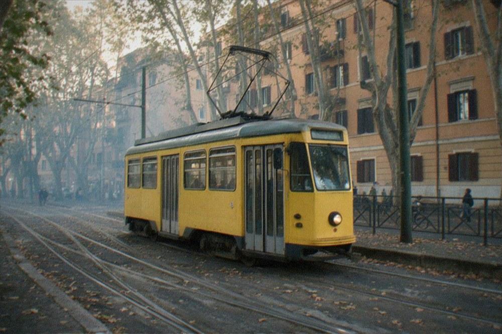 A Roman tram moving along a tree-lined street with old apartment buildings behind it