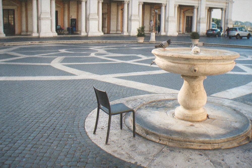 Cobblestone square with a fountain and museum facade in morning light