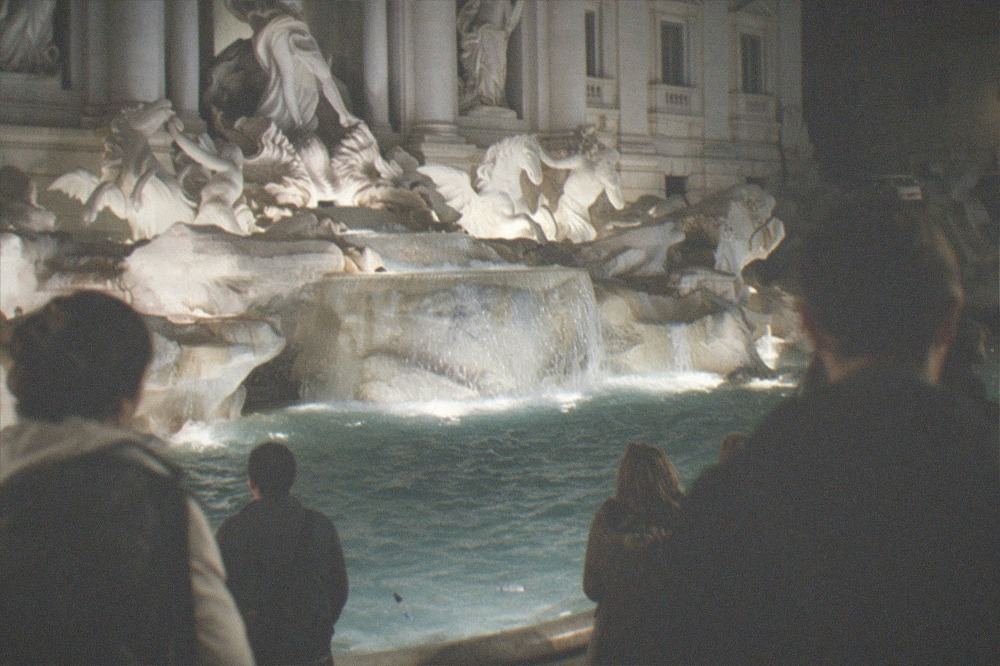 Trevi Fountain illuminated at night with baroque sculpture lit against dark sky