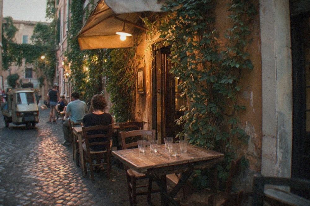Ivy covered trattoria facade and lamplit cobbles at dusk