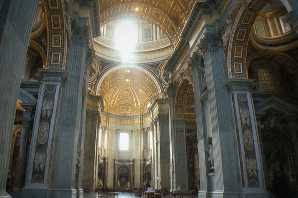 Interior of St Peter's Basilica with tall columns and light from the dome