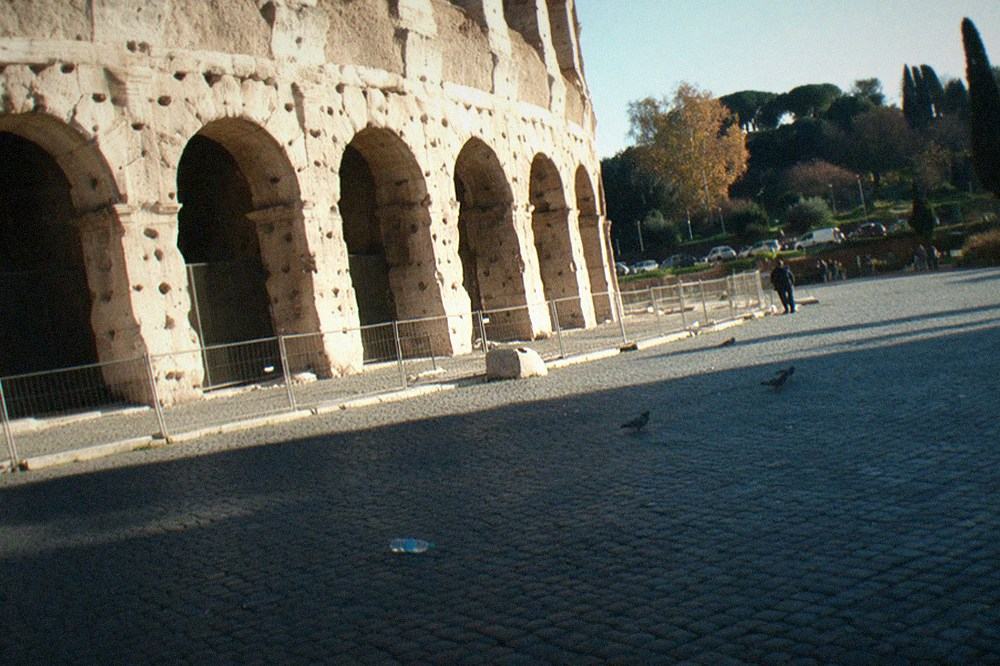 The ancient stone arches of the Colosseum exterior seen from a public square